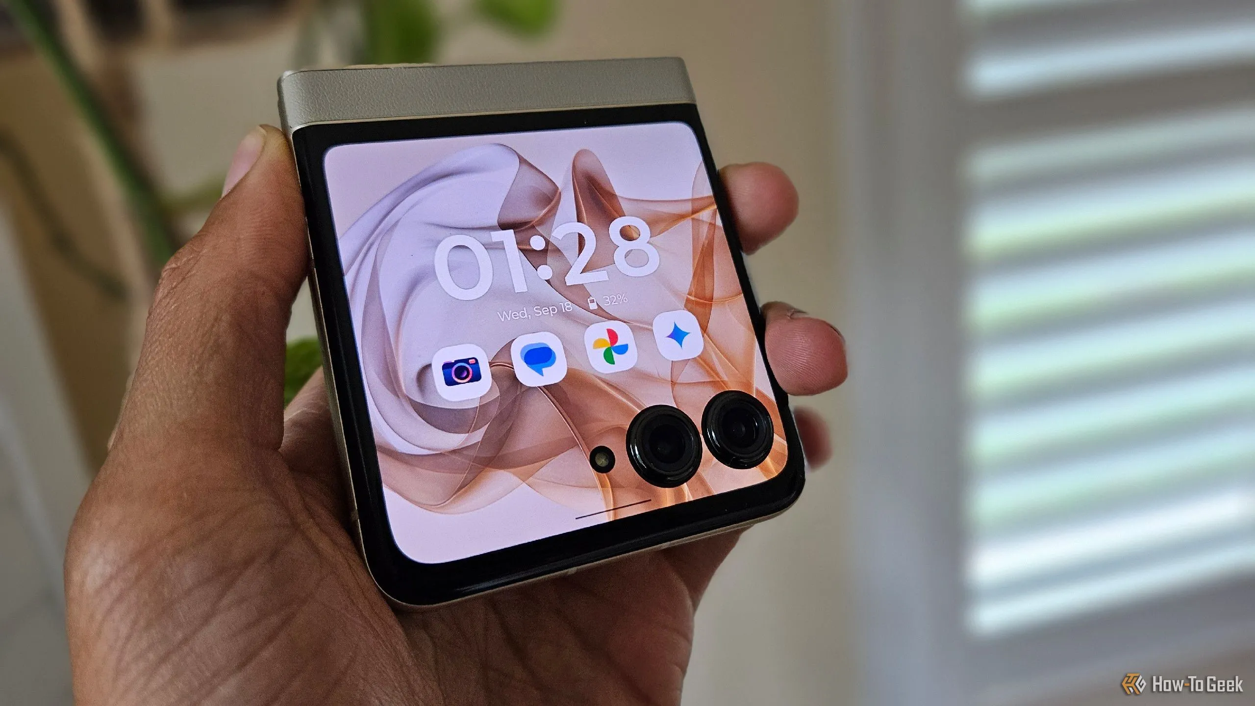 Bàn tay đang cầm điện thoại gập Moto Razr 2024 ở trạng thái gập, cho thấy độ dày của thiết bị