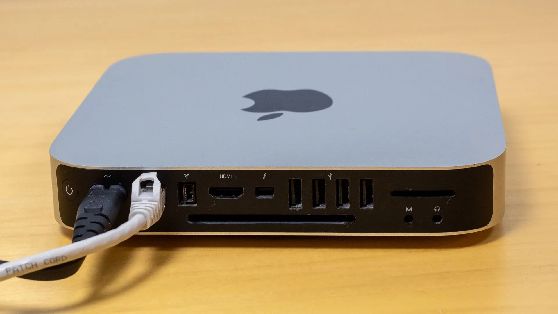 Các cáp Ethernet và nguồn được cắm vào mặt sau của Mac mini, cho thấy khả năng kết nối mạng ổn định và nguồn điện cho thiết bị.