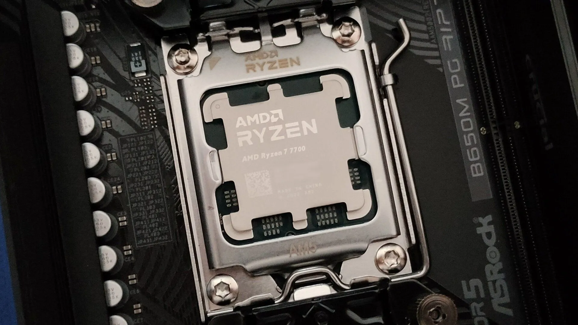 Cận cảnh bộ vi xử lý AMD Ryzen 7 7700 trên socket AM5 cùng bo mạch chủ ASRock B650M PG Riptide, minh họa linh kiện nền tảng cho hiệu suất gaming cao.