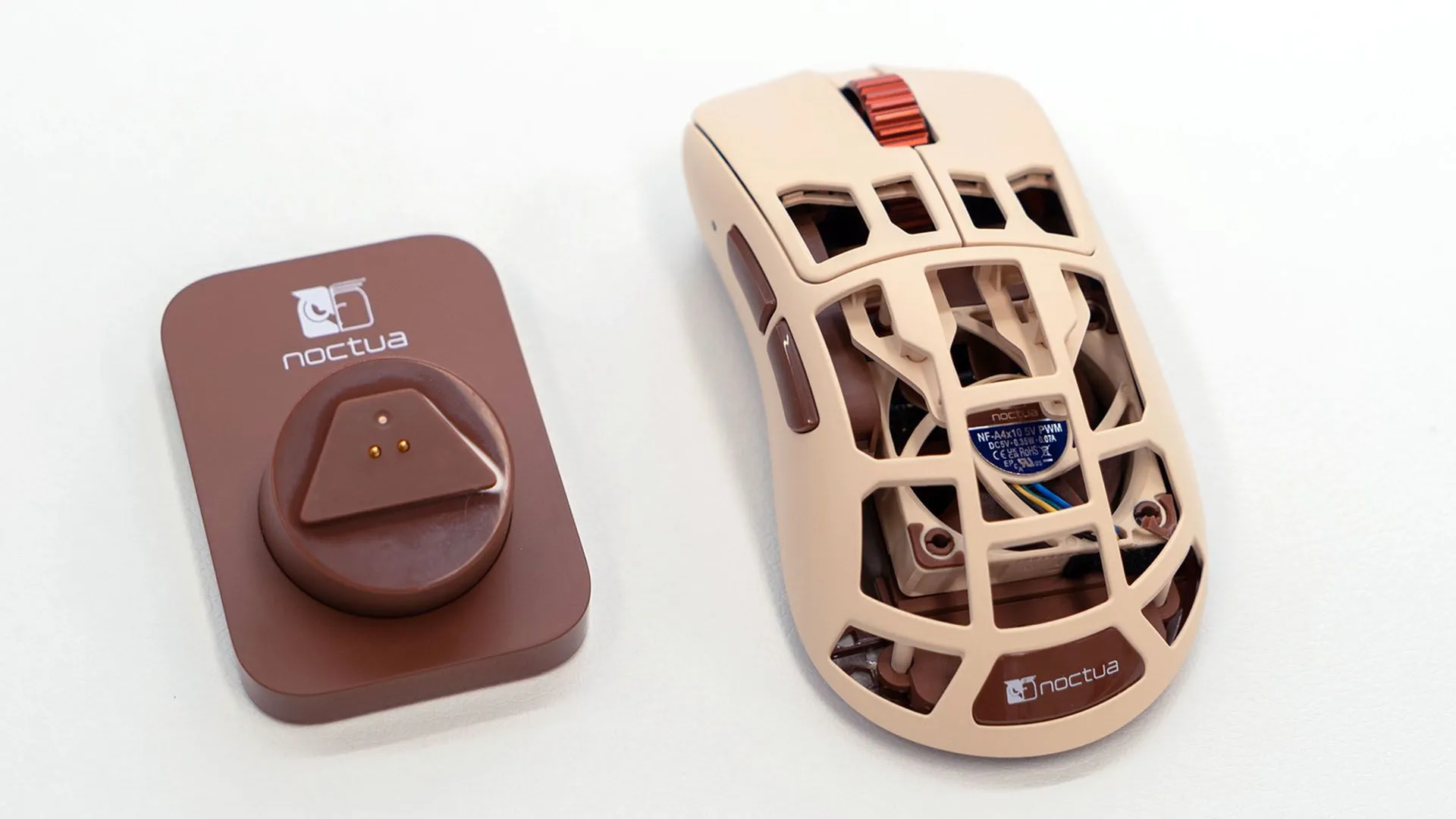 Chuột Pulsar x Feinman Noctua Edition cùng đế sạc, thể hiện thiết kế lỗ thoát khí và quạt tản nhiệt.