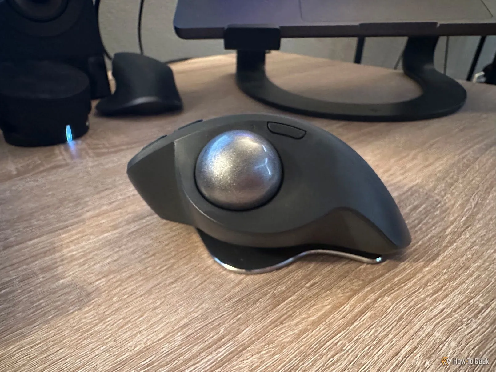 Chuột trackball Logitech MX Ergo S đặt trên mặt bàn làm việc, góc chụp cận cảnh làm nổi bật bi lăn và nút bấm, minh họa sự kết hợp joystick và chuột khi chơi game