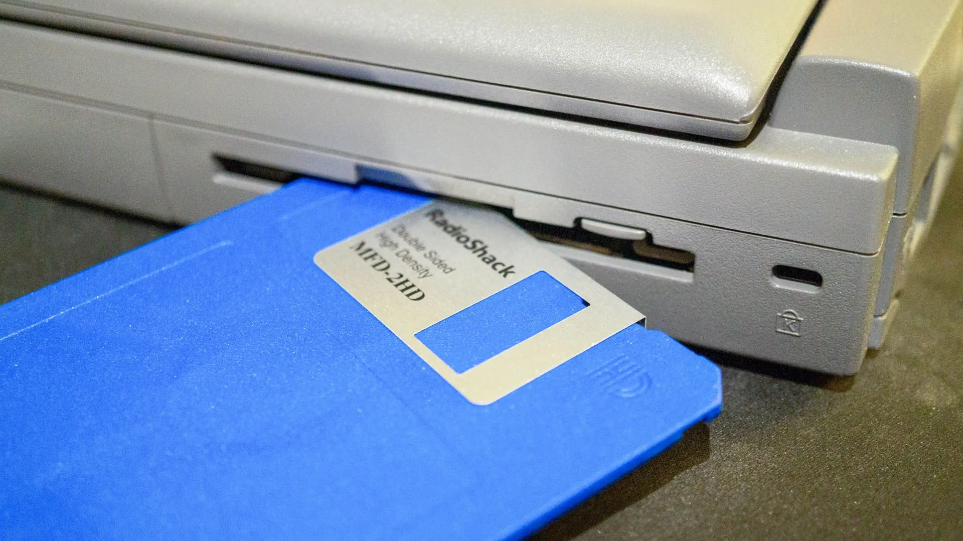 Đĩa mềm floppy disk và ổ đĩa được sử dụng để truy cập dữ liệu trên laptop, thể hiện sự hoài niệm về thời kỳ lưu trữ cơ bản của máy tính.
