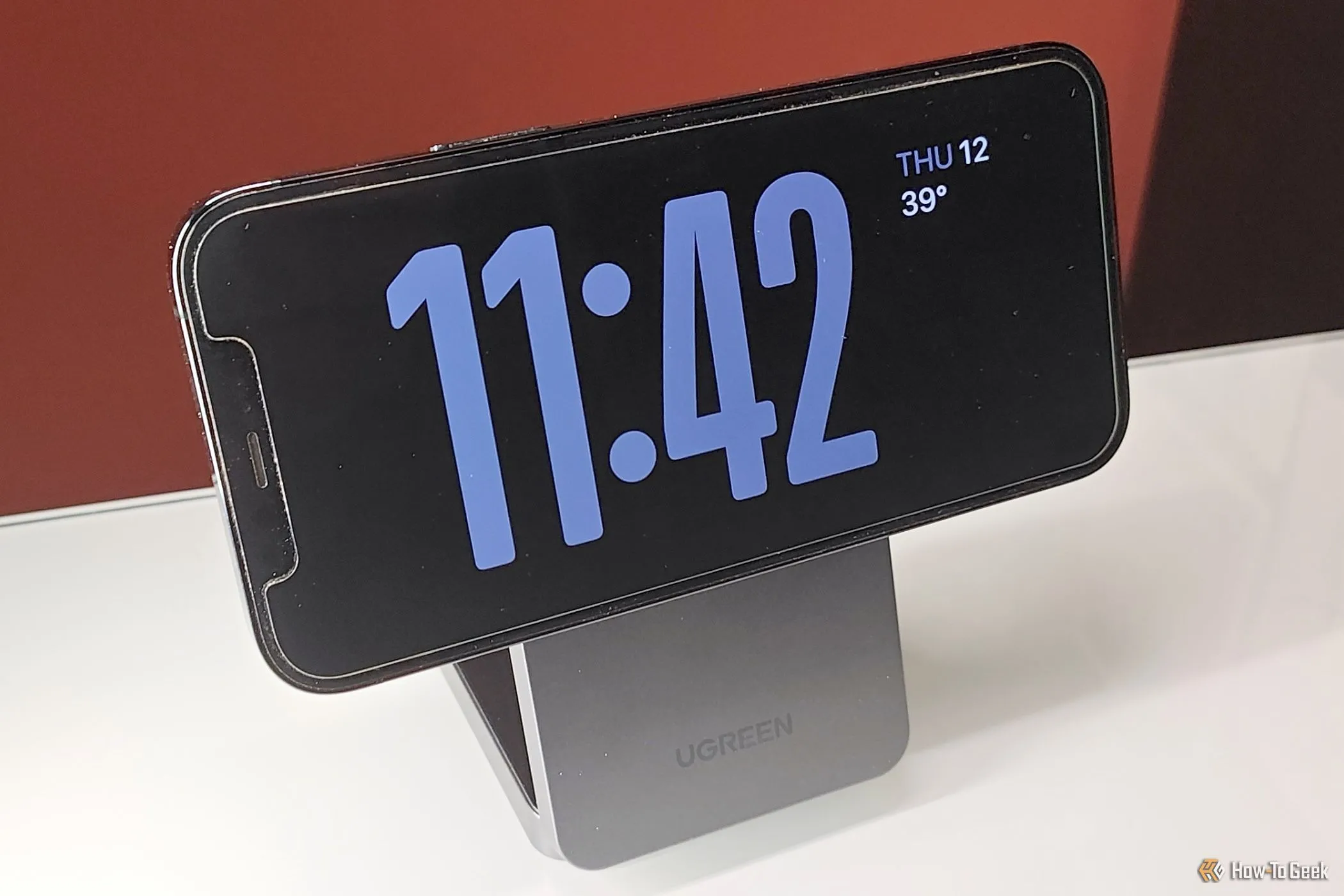 Giá đỡ điện thoại MagFlow Qi2 đang giữ iPhone ở chế độ StandBy, tối ưu góc nhìn để xem thông báo và giờ.