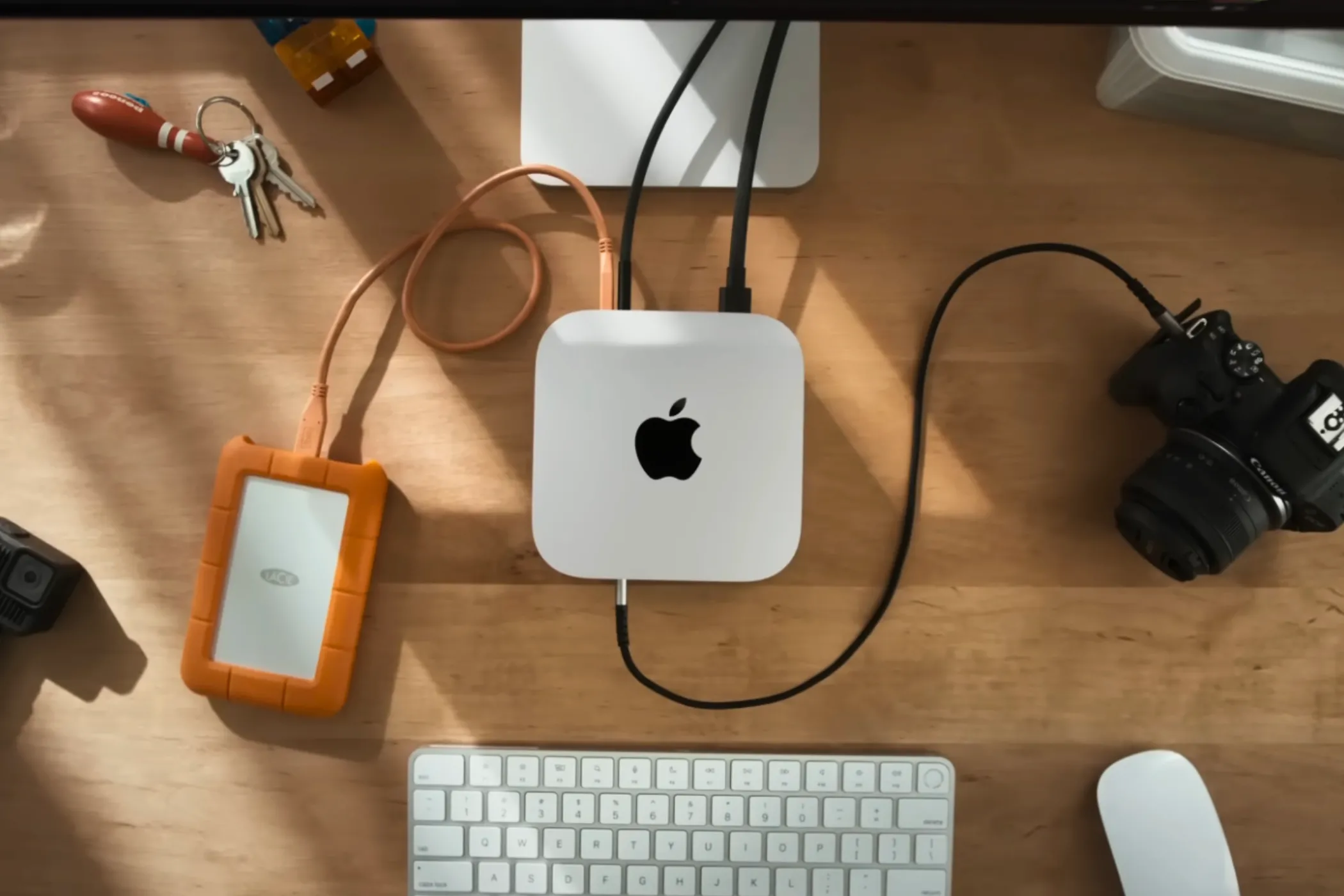 Góc nhìn từ trên xuống của Mac mini M4 trên bàn làm việc, được bao quanh bởi các phụ kiện như bàn phím và chuột, thể hiện khả năng tích hợp vào không gian làm việc.