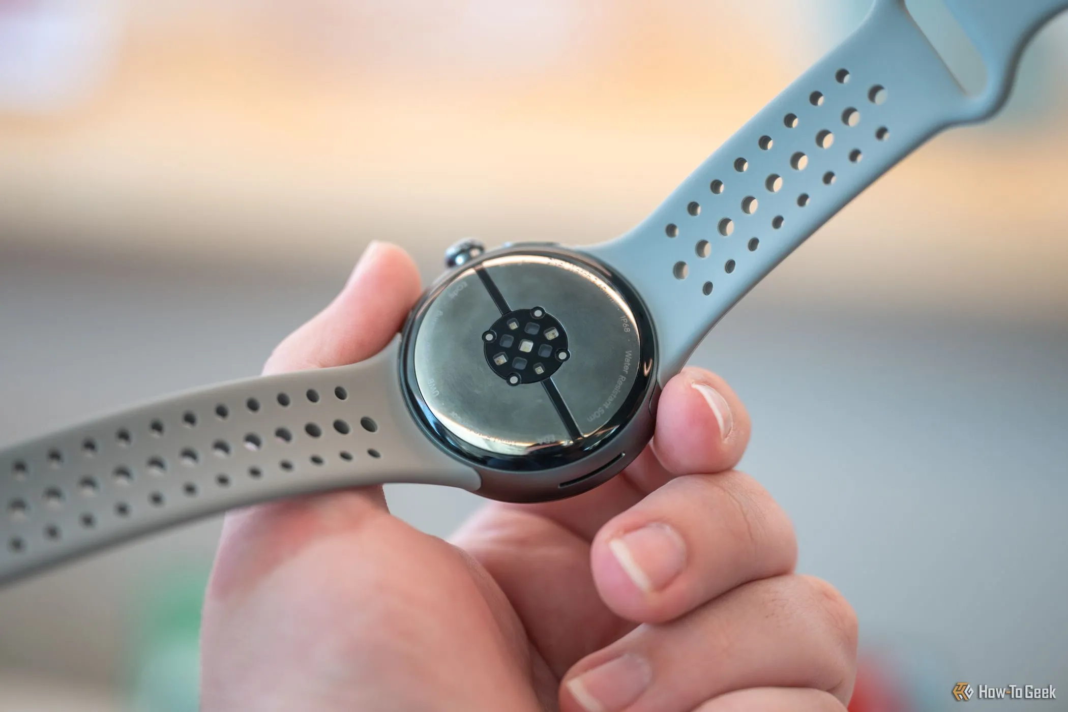 Google Pixel Watch 3 trong tay người dùng, làm nổi bật thiết kế bo tròn và cảm biến dưới đáy.