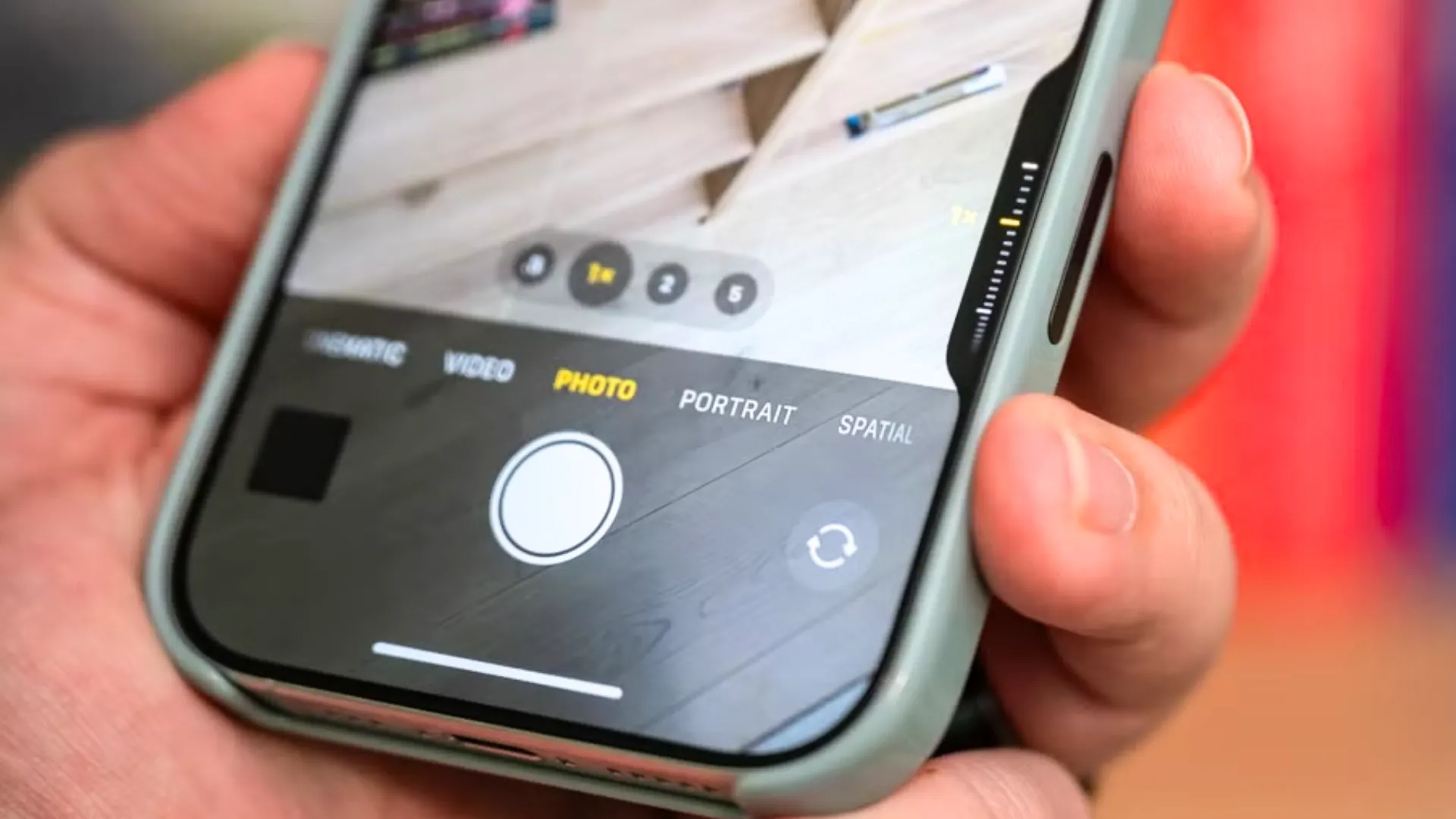 iPhone 16 cầm trên tay, ngón cái đặt gần nút Camera Control mới, giúp truy cập nhanh tính năng chụp ảnh