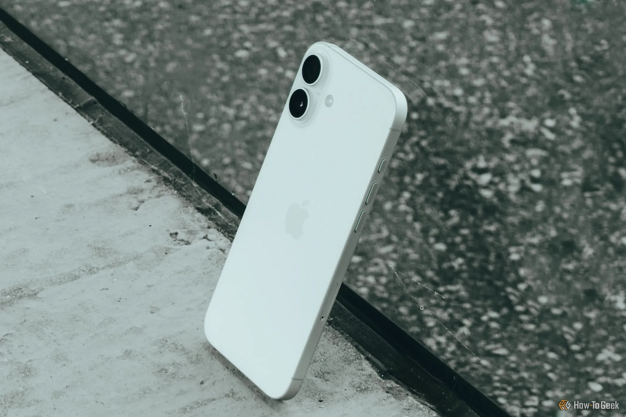 iPhone 16 Plus màu xanh nằm trên mặt kính, thể hiện thiết kế sang trọng và màn hình lớn