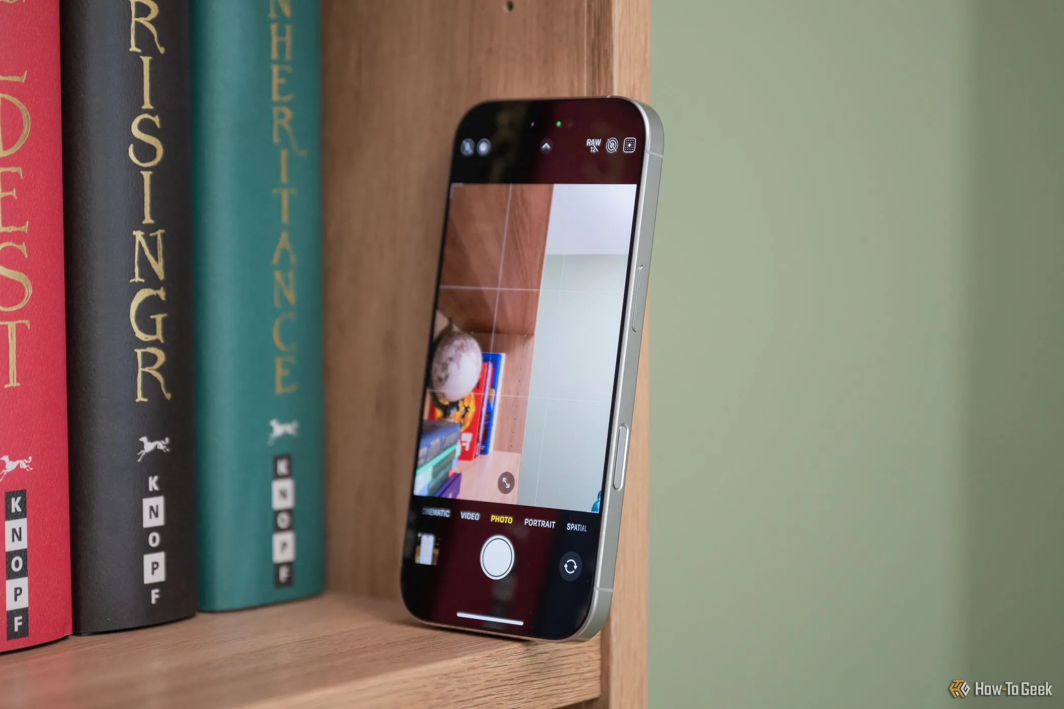iPhone 16 Pro đặt trên giá sách, hiển thị giao diện điều khiển camera với các tùy chỉnh chuyên sâu