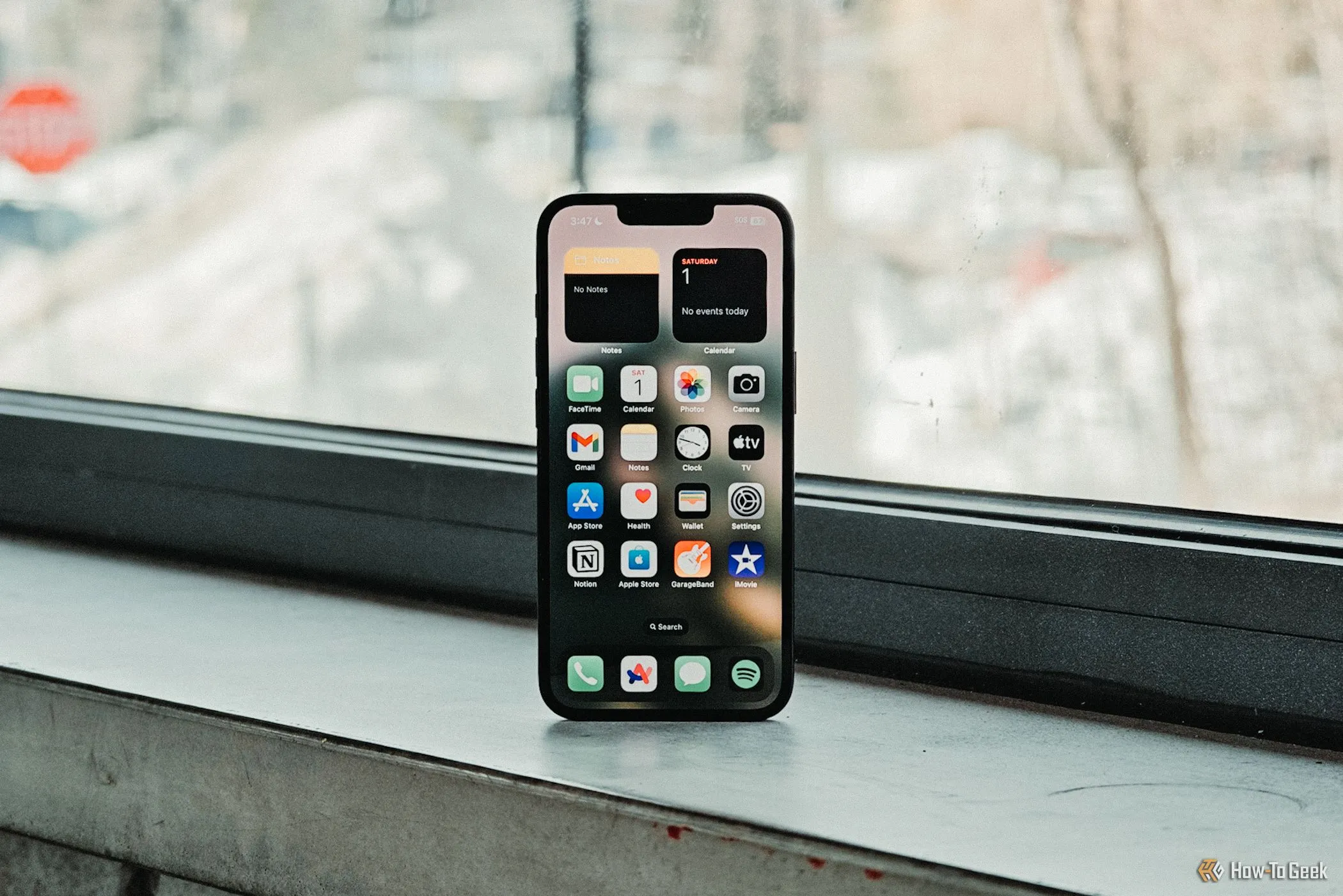 iPhone 16e hiển thị màn hình chính trước cửa sổ, thể hiện giao diện người dùng và thiết kế mặt trước.