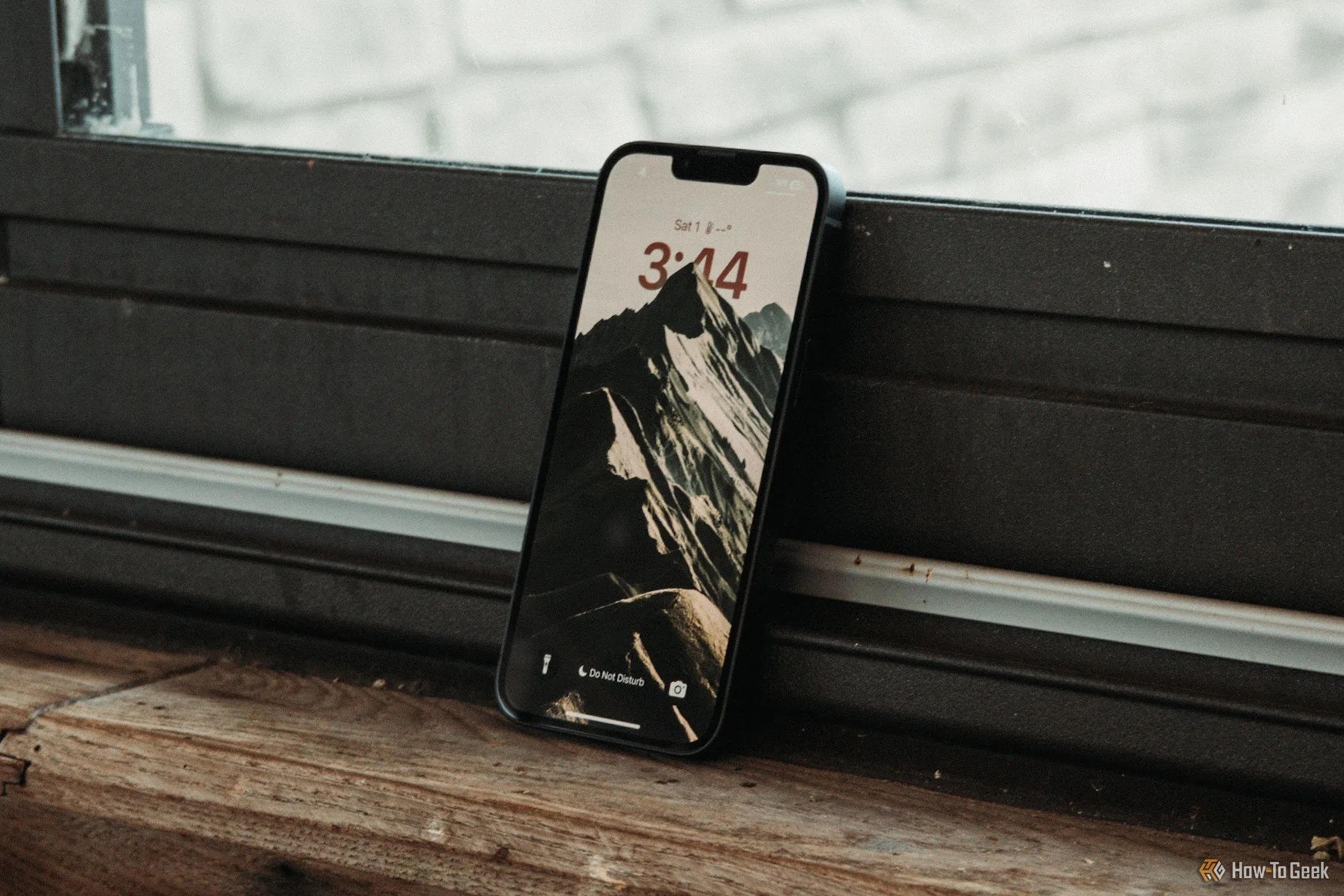 Màn hình khóa iPhone 16e tựa vào cửa sổ, minh họa trải nghiệm hiển thị.