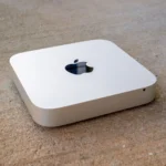 Một chiếc máy tính Mac Mini đặt trên bề mặt bê tông, thể hiện sự nhỏ gọn và thiết kế đặc trưng của sản phẩm Apple.