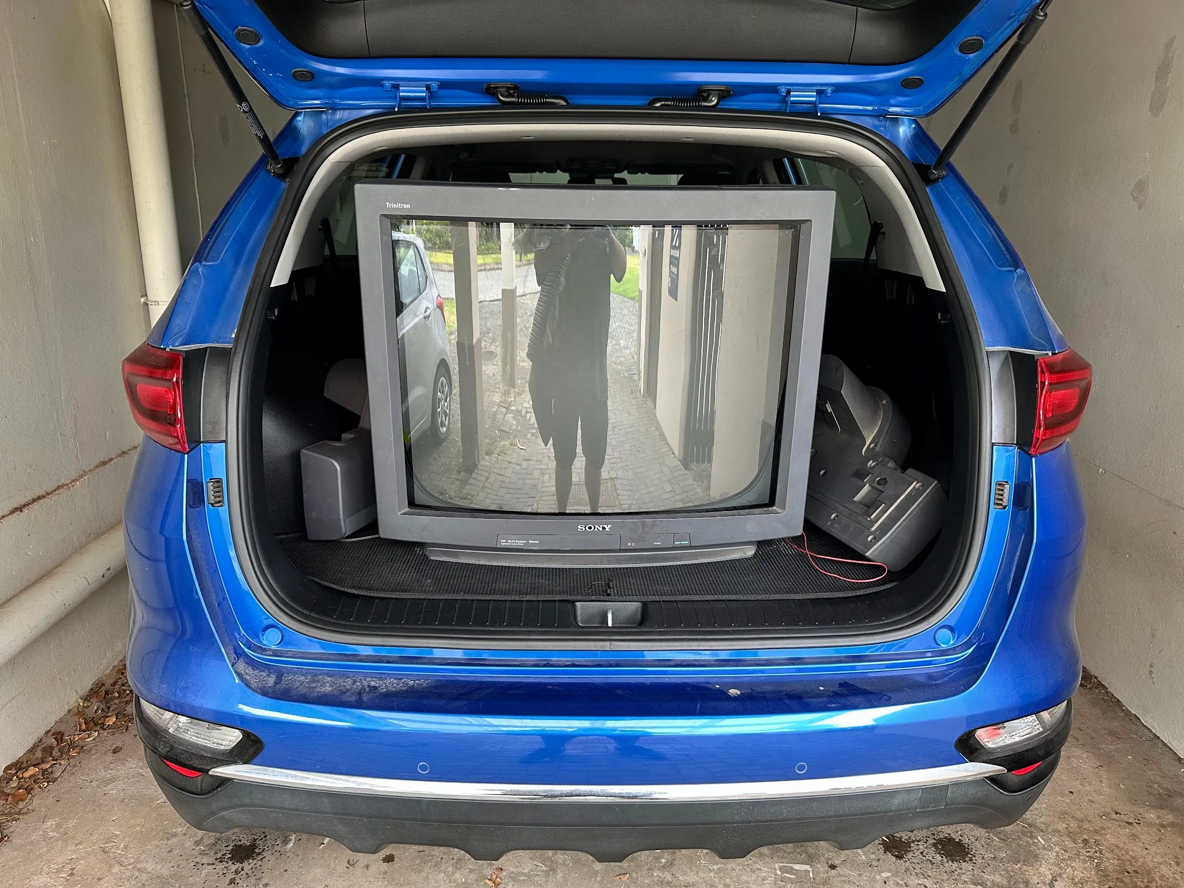 Một chiếc TV CRT Sony lớn được chất ở khoang sau xe SUV Kia Sportage, minh họa rõ ràng kích thước cồng kềnh và sự khó khăn khi vận chuyển màn hình CRT.