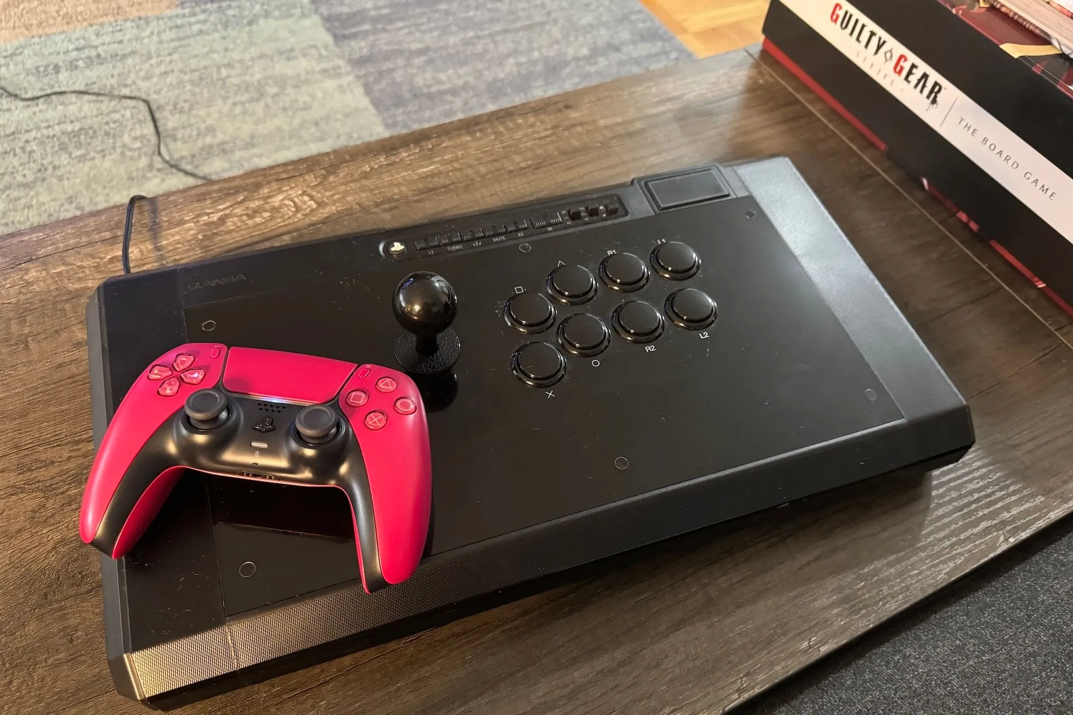 Một tay cầm DualSense PS5 đặt trên bàn đấu game đối kháng (fight stick)