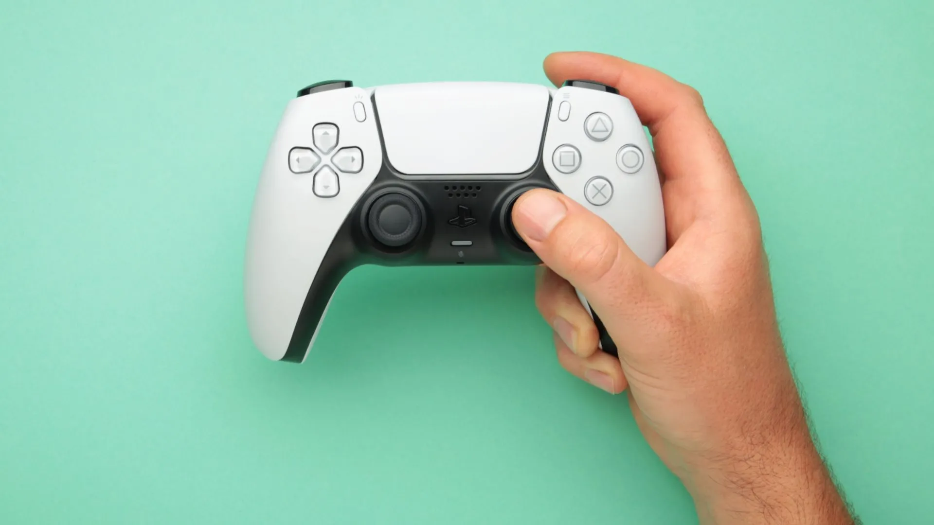 Người đàn ông cầm tay cầm không dây DualSense với một tay, sẵn sàng cho trải nghiệm chơi game trên Mac.