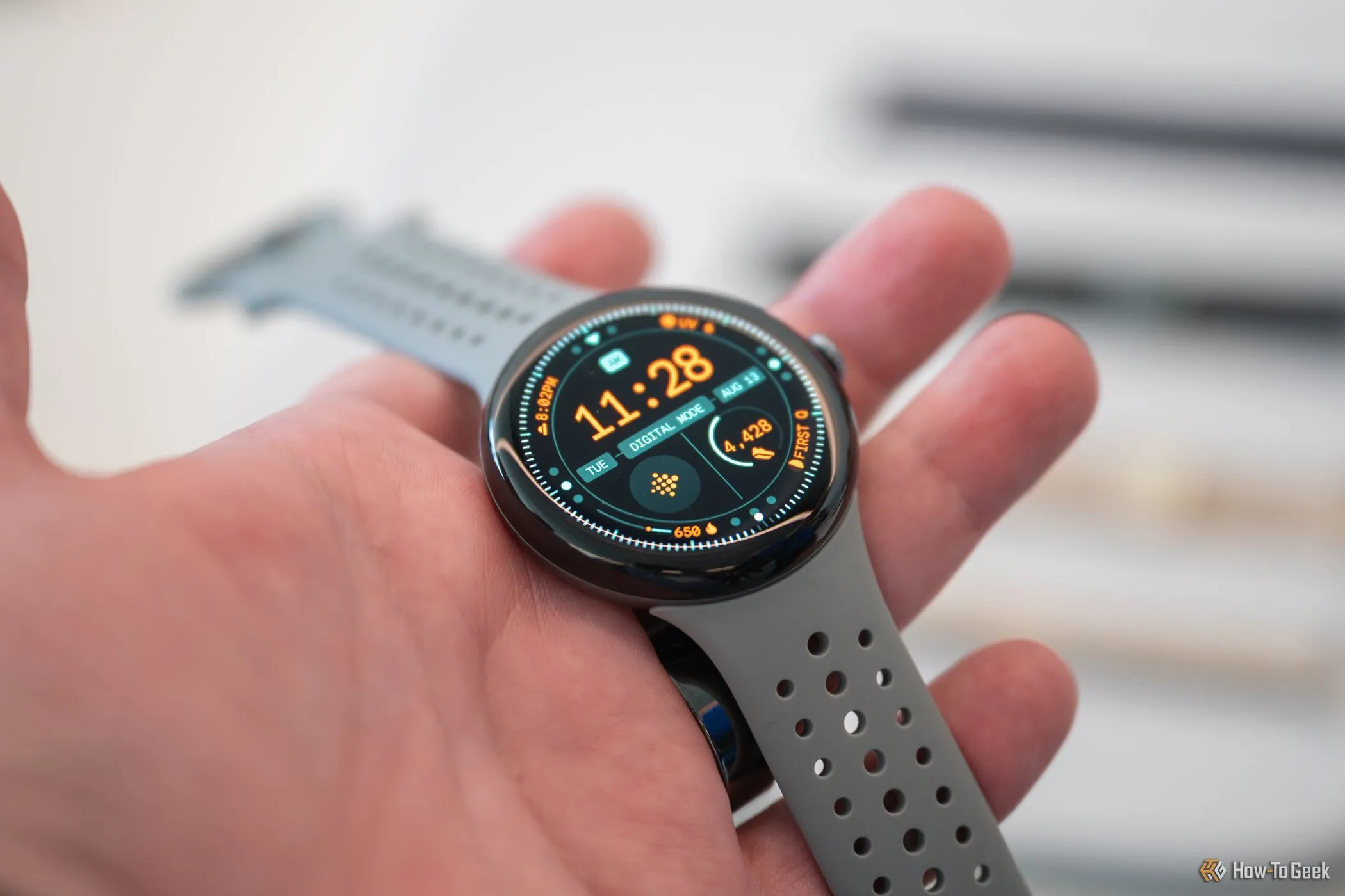 Người dùng cầm trên tay Google Pixel Watch 3 hiển thị màn hình, thể hiện thiết kế tròn và kính cong vòm đặc trưng.