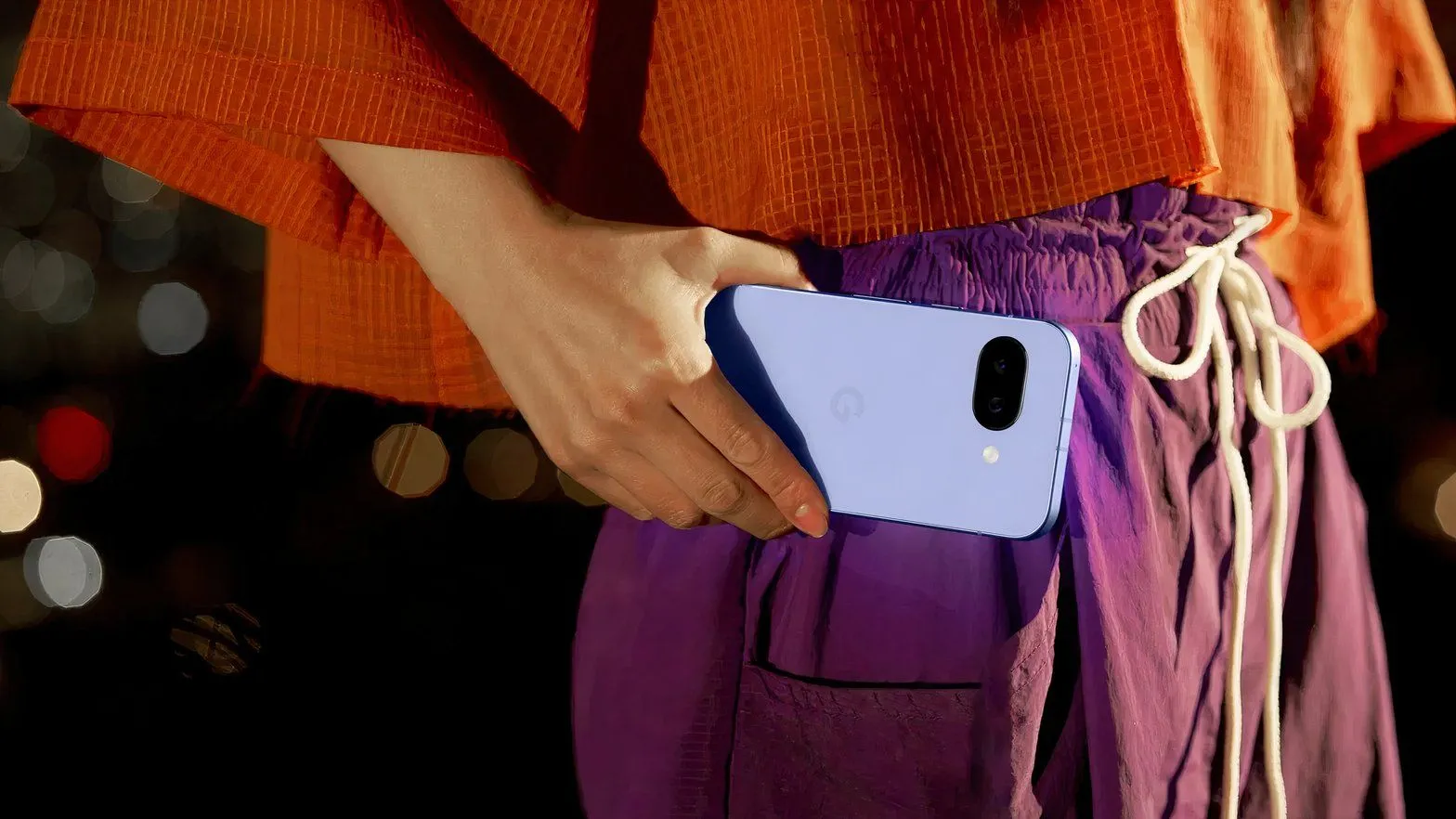 Người phụ nữ cầm điện thoại Google Pixel 9a ở thắt lưng, thể hiện khả năng chụp ảnh.
