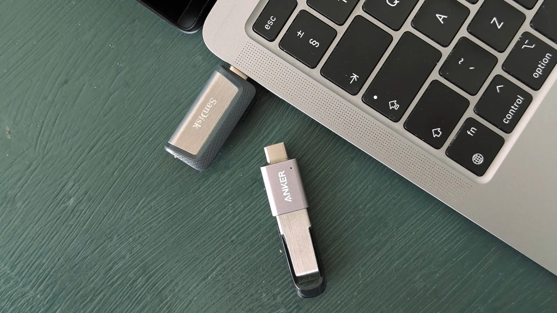 Nhiều chiếc USB flash drive với các kích thước và cổng kết nối khác nhau đặt cạnh MacBook, minh họa sự đa dạng và tiến hóa của thiết bị lưu trữ di động