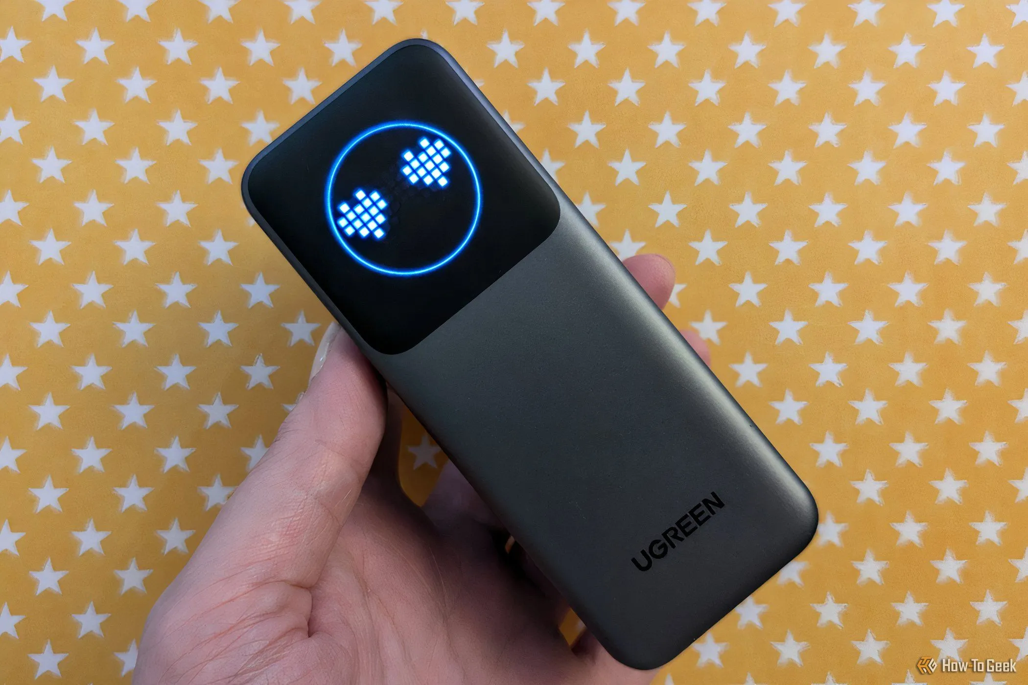 Sạc dự phòng Ugreen Nexode 12000mAh với màn hình hiển thị emoji đang sạc một chiếc điện thoại