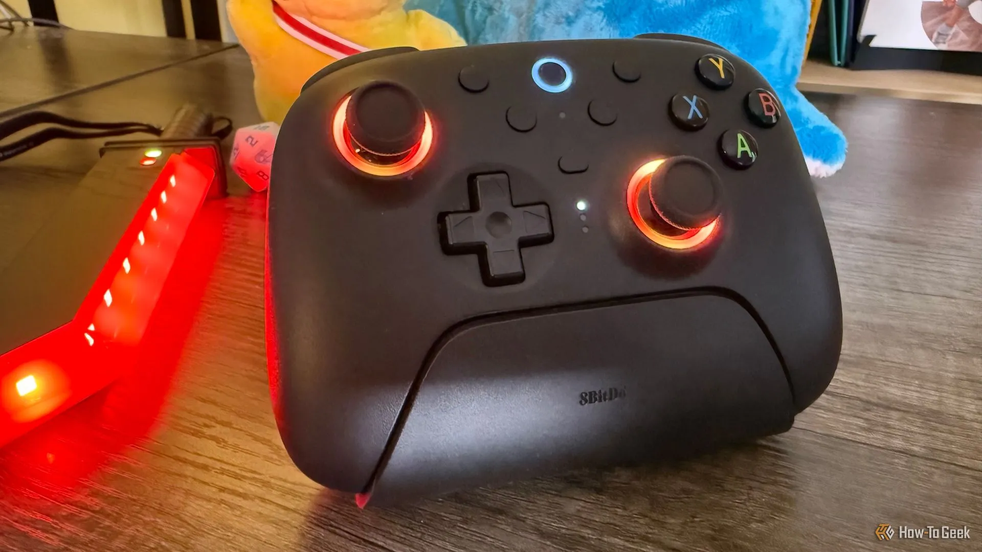 Tay cầm 8BitDo Ultimate 2 Wireless với đèn LED vòng quanh joystick màu đỏ, minh họa tính năng ánh sáng RGB