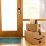 Thùng hàng Amazon được đặt trước cửa nhà, biểu tượng của việc mua sắm trực tuyến và trả hàng.